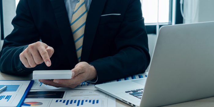 Businessman’s hands pressing a calculator, calculating, analyzing, graphing, charting, accounting worker working on a laptop. A bank clerk who advises making financial reports or company profits. Businessman's hands pressing a calculator, calculating, analyzing, graphing, charting, accounting worker working on a laptop. A bank clerk who advises making financial reports or company profits.